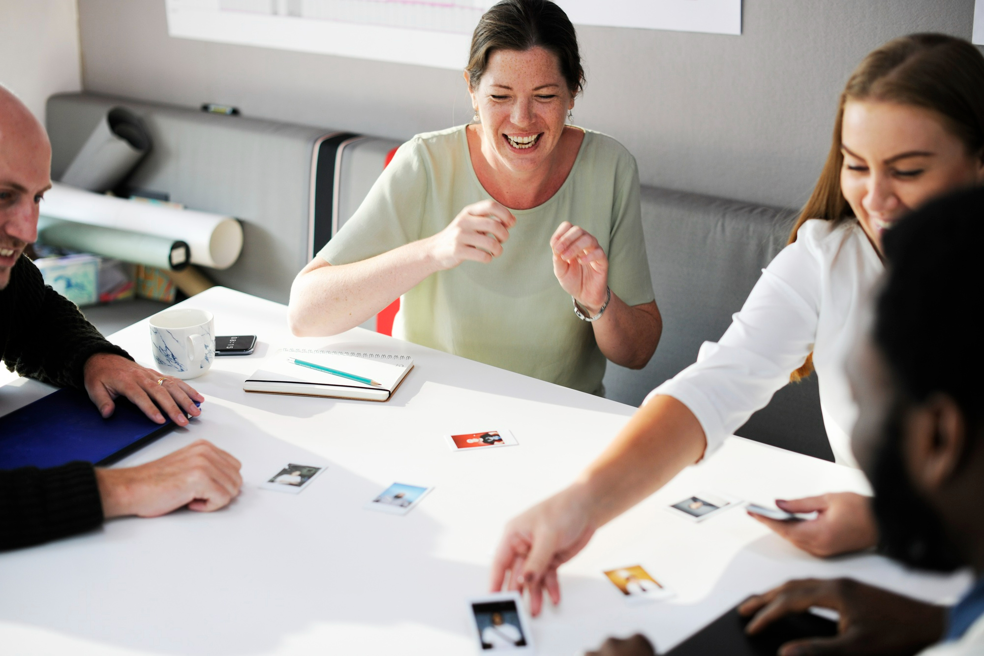 Atelier de formation pour adultes utilisant la ludopédagogie : groupe d'apprenants engagés manipulant des cartes, illustrant l'objectif de concevoir un jeu pédagogique avec l'IA.