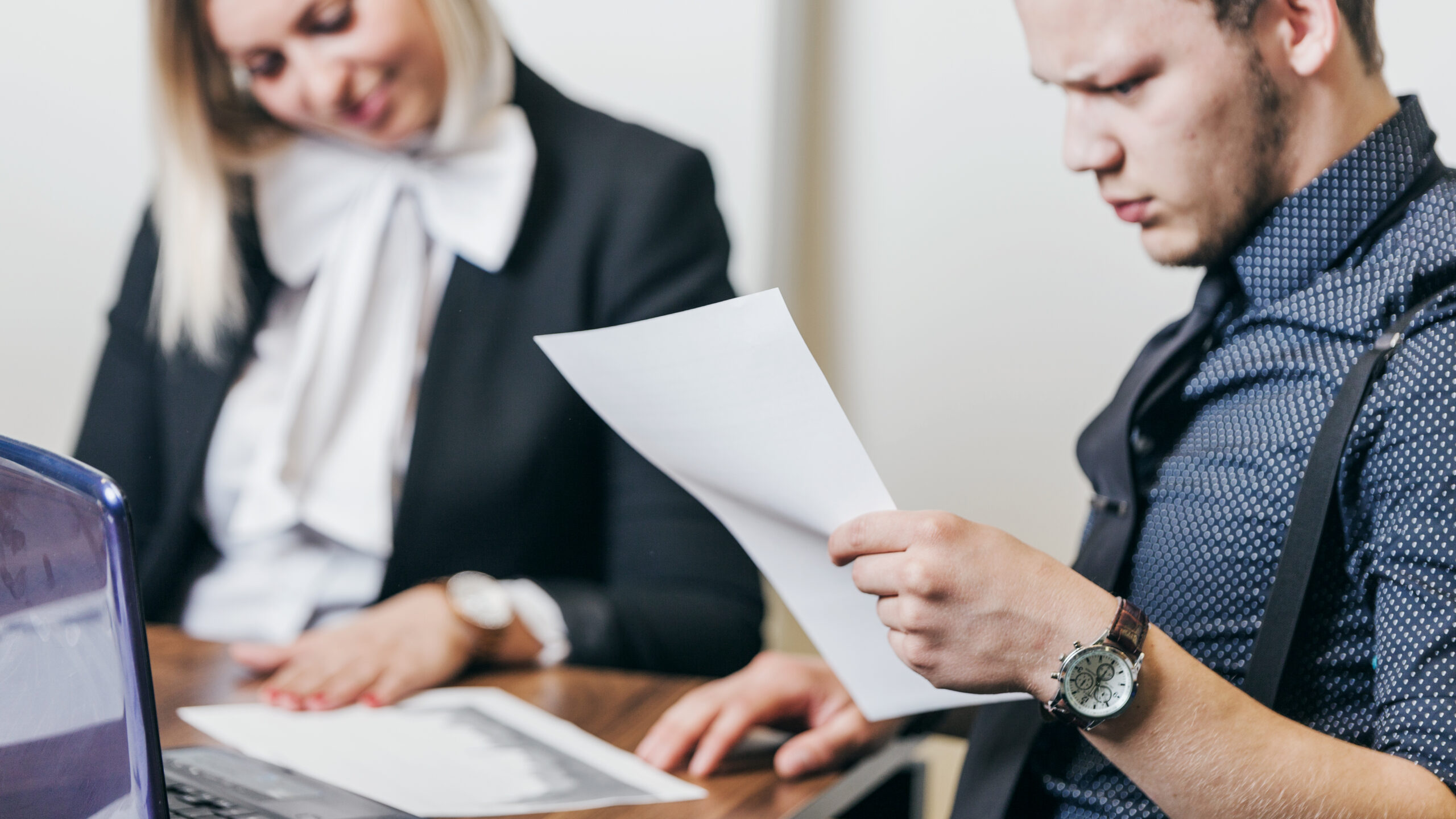 un homme et une femme assis a table de travail et regardent les documents pour l'audit qualiopi
